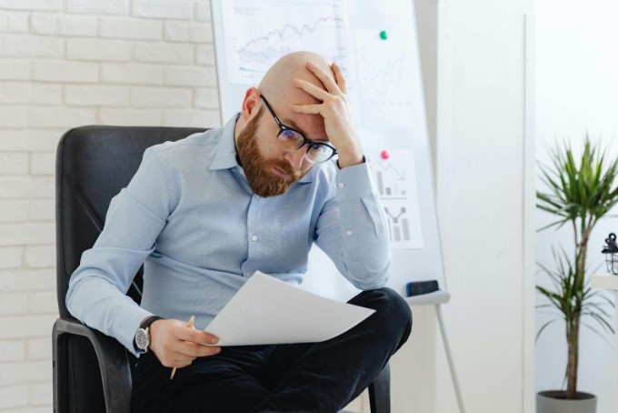 Stressed professional reading a termination letter alone in office, visibly concerned about job loss.