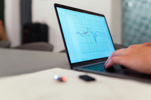 Technician analyzing electric motor performance data on a laptop, displaying predictive maintenance graphs and sensor diagnostics for industrial equipment. 